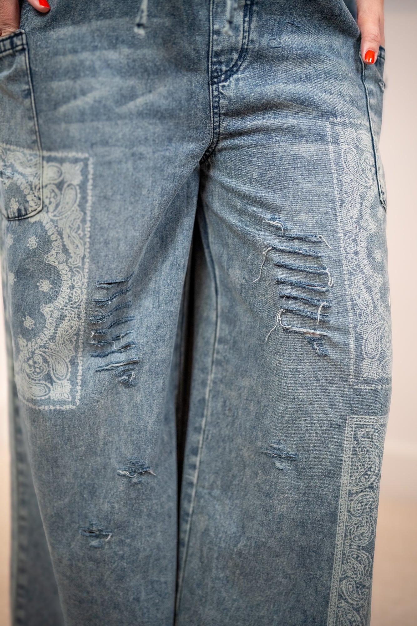 Close-up of distressed blue jeans with patterned patches.