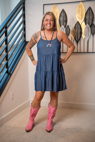 Blue tiered denim babydoll dress with spaghetti straps worn with pink cowboy boots