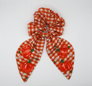 Orange and white checkered scrunchie with pumpkin design on a white background