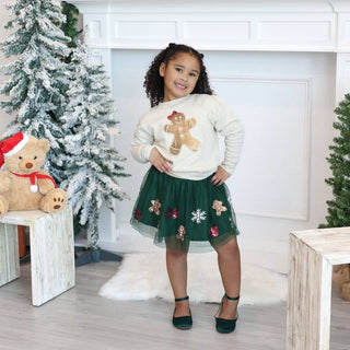 Girl wearing green tulle skirt with gingerbread sequin appliqués and matching cream sweater