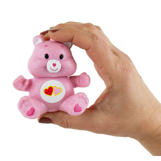 Hand holding pink Care Bears stretchable figure with hearts on belly