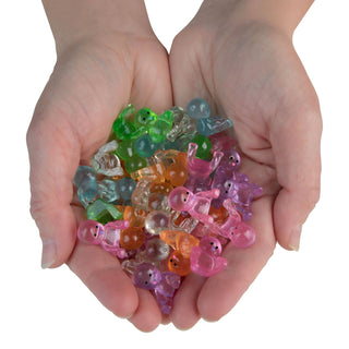 Colorful transparent jelly candy shaped like ducks held in hands against a white background