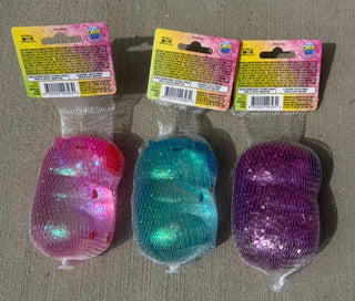 Three colorful squishy toys in packaging on a textured surface