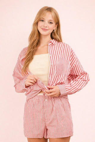 Woman wearing a red and white striped shirt and shorts set on a pink background