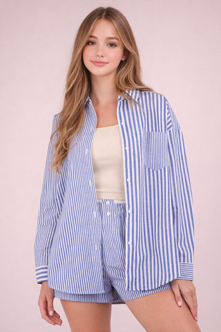 Woman wearing a blue and white striped shirt and shorts on a pink background