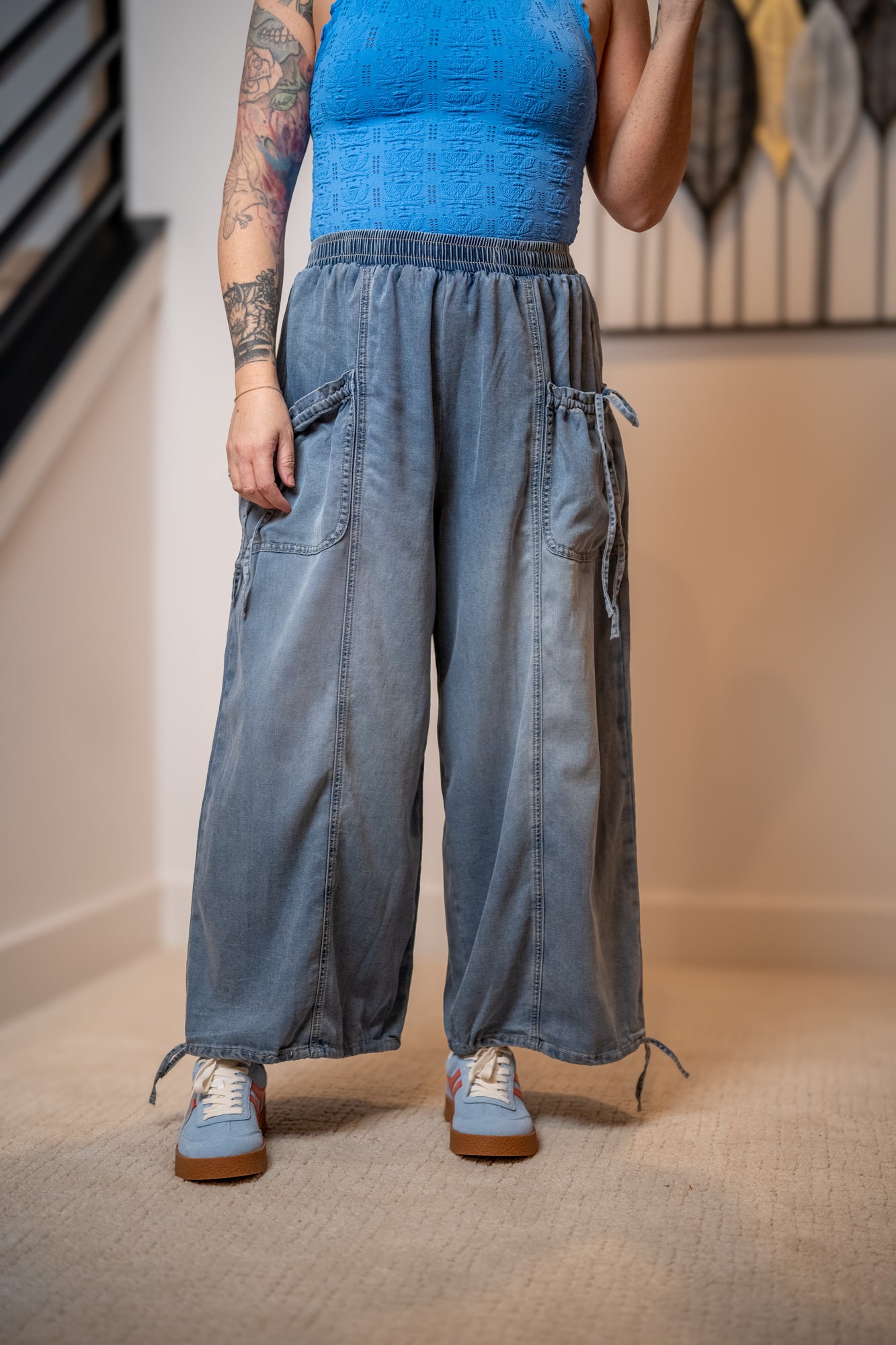 Person wearing blue lace tank top and flowy easel pants with pocket details and adjustable hem tie