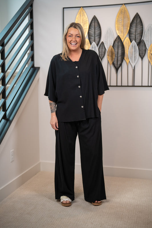 Woman wearing a black outfit standing in a room with decorative wall art.