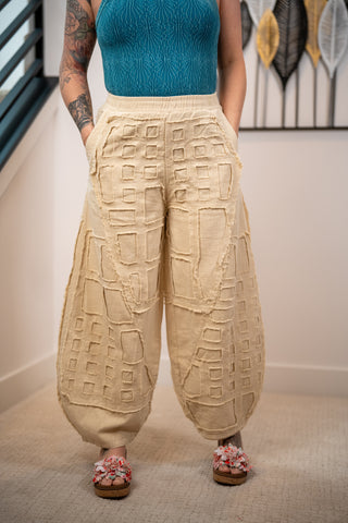 Person wearing a blue top and beige textured pants in an indoor setting.