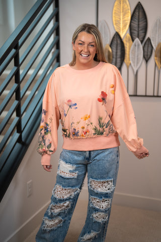 woman wearing dolman coral pullover top with floral print on body and sleeves