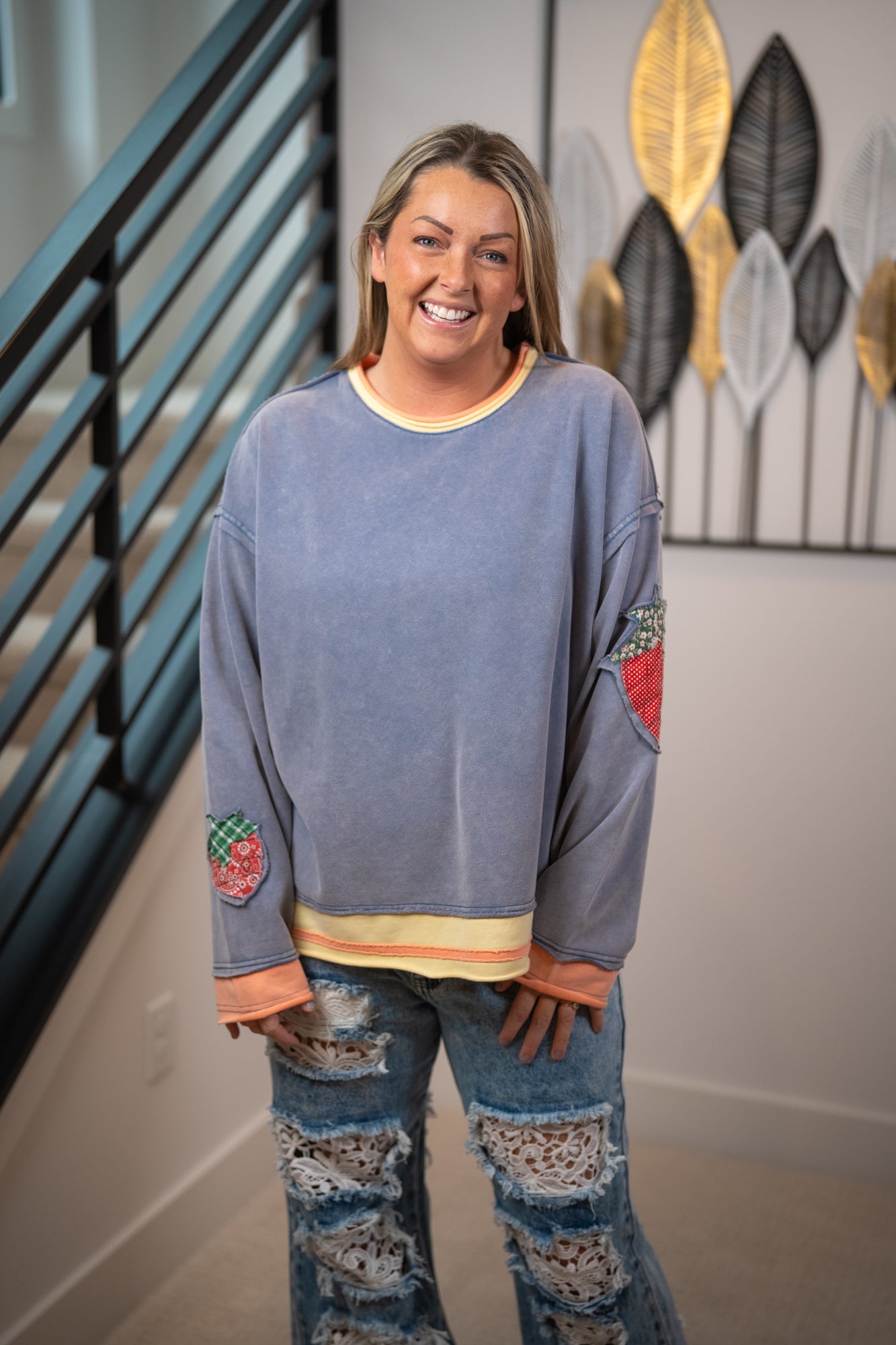 Woman wearing a blue sweater with colorful arm patches in a home setting