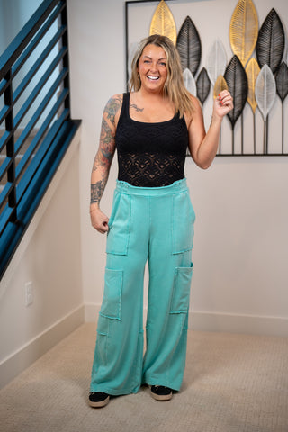 Woman wearing a black lace tank top nikibiki and teal lounge pants 