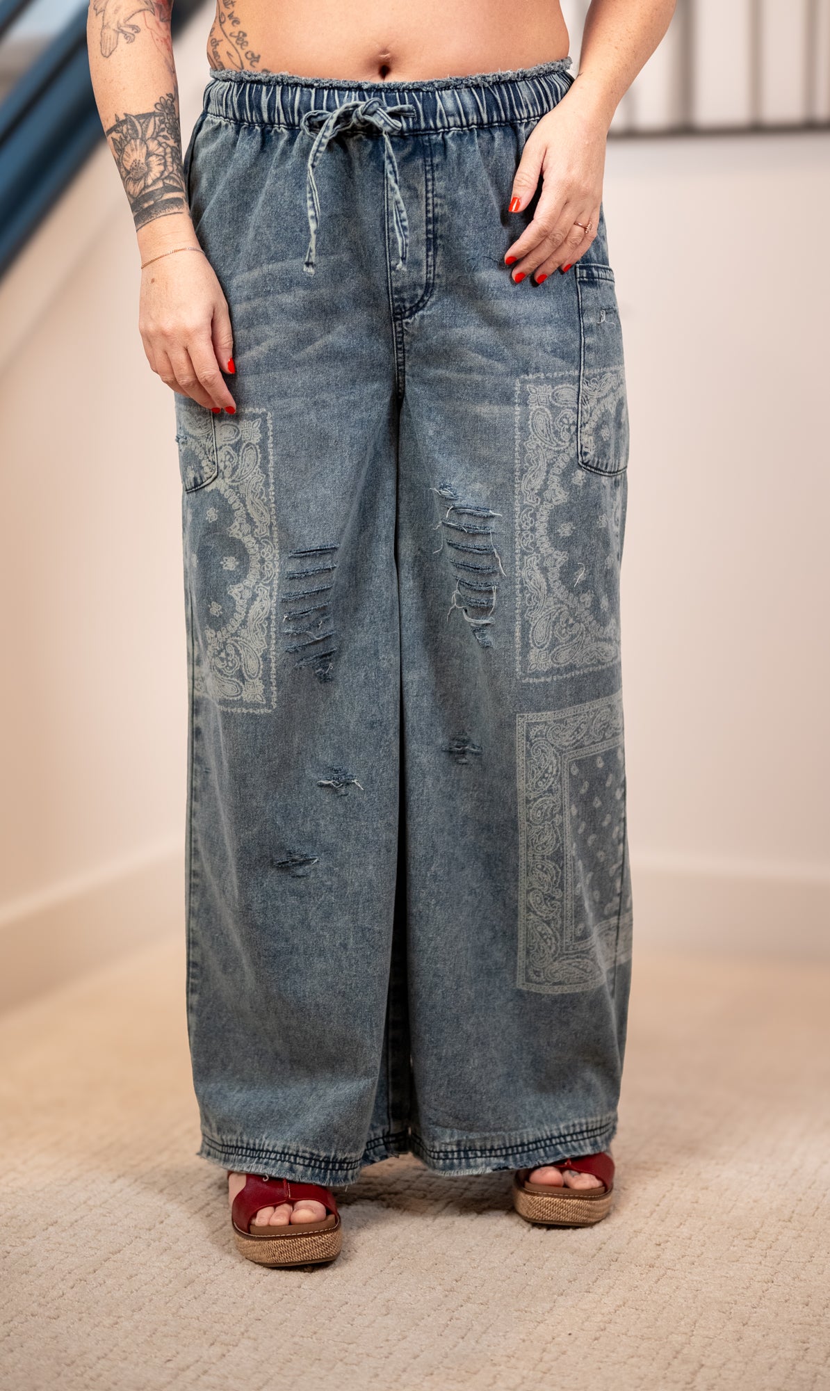 Wide-leg jeans with patchwork design worn by a person indoors.