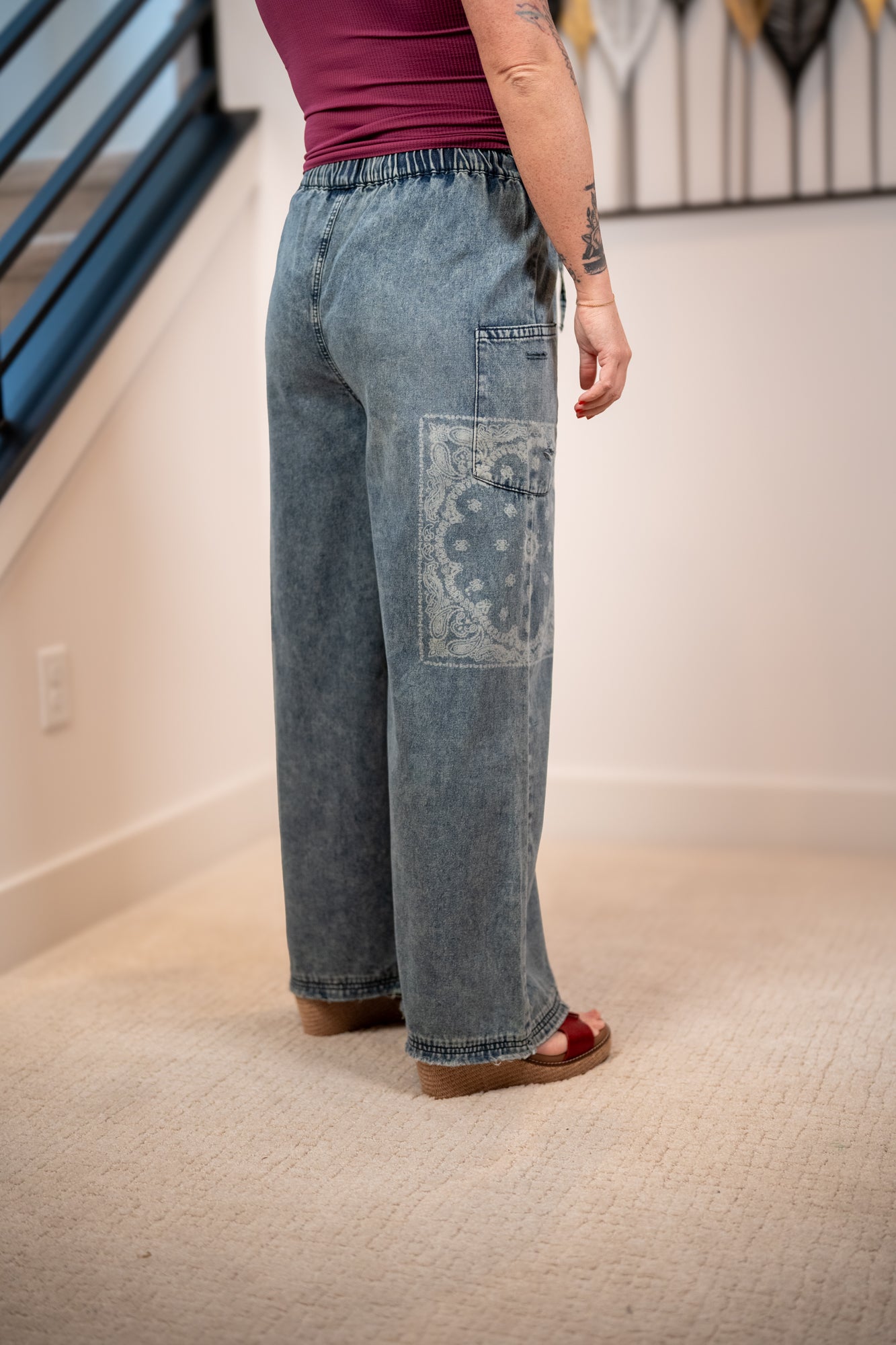 Person wearing blue jeans with a floral patch in an indoor setting