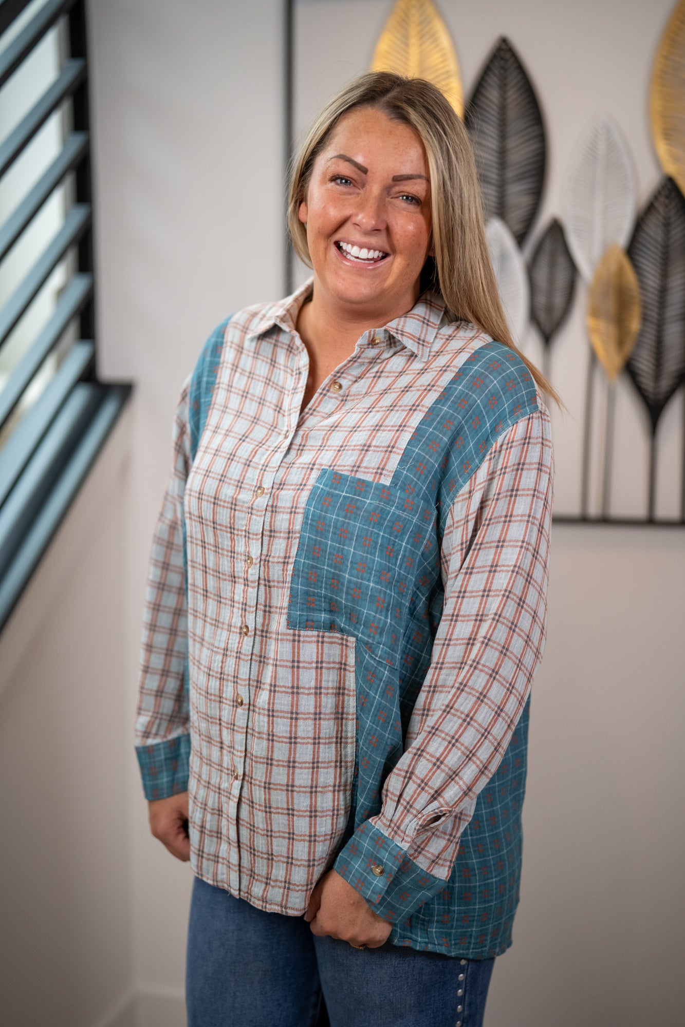 Woman wearing a plaid shirt with blue accents in a room with decorative wall art.