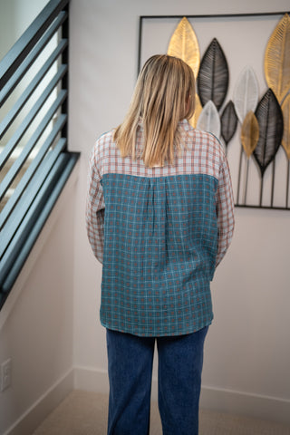 Person wearing a plaid shirt over a green checkered vest in a room with wall art.