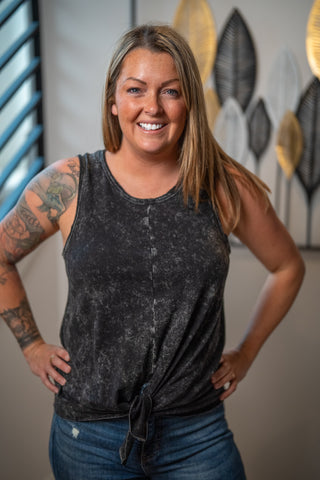 Woman wearing a black sleeveless top with a blurred background