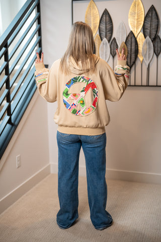 Tan hoodie with colorful patchwork peace sign graphic on back, wide-leg jeans