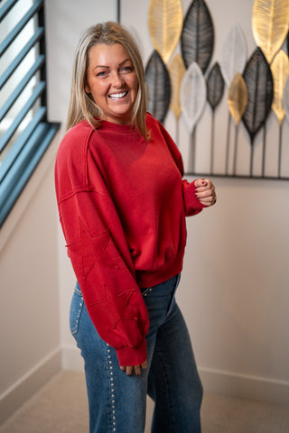 Red crewneck sweatshirt with tonal star patches along the sleeves