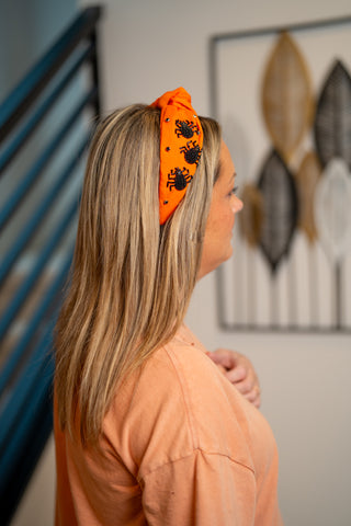 Orange knotted headband with beaded black spiders and crystal accents on blonde hair