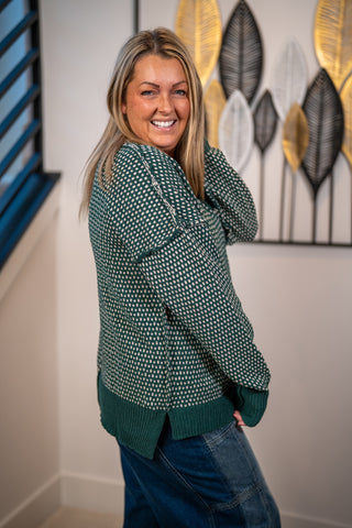 Green and cream contrast knit sweater with ribbed hem, worn with blue jeans