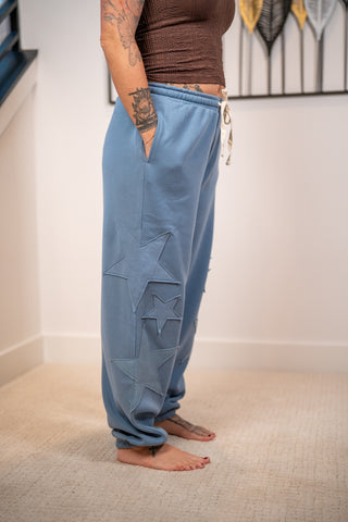 Blue jogger sweatpants with tonal star appliqué patches and white drawstring tie