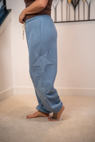Blue jogger sweatpants with tonal star appliqué patches and drawstring waist