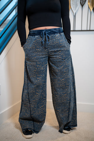 Person wearing blue patterned pants and a black top indoors.