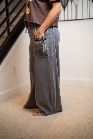 Person wearing gray drawstring pants standing on a carpeted floor.
