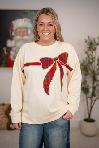 Cream pullover sweatshirt with red tartan plaid bow appliqué and gold sequin trim