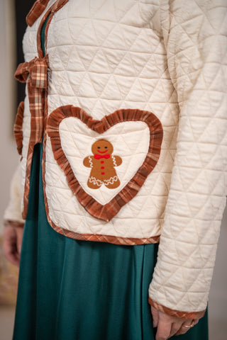 Cream quilted jacket with heart-shaped gingerbread man pocket and brown plaid trim