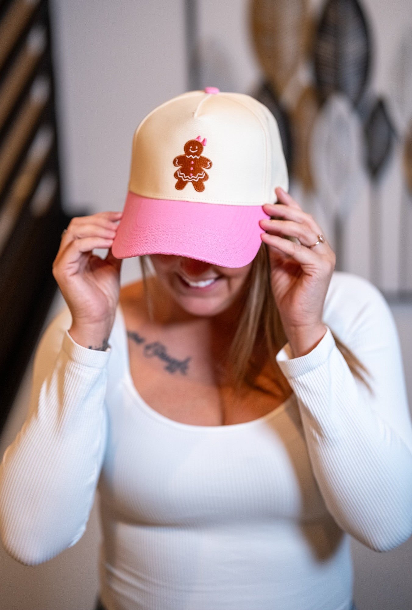 Woman adjusting the Pink Sugar Gingerbread Girl Cap with embroidered gingerbread design.