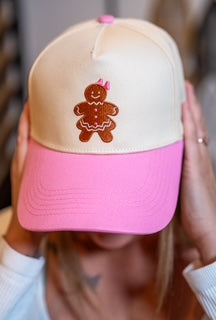 Close-up of gingerbread girl embroidery on cream crown and pink bill.