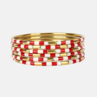 Stack of red and white striped bangles with gold accents on white background