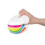 Hand squeezing white rainbow-striped cake-shaped squishy stress toy