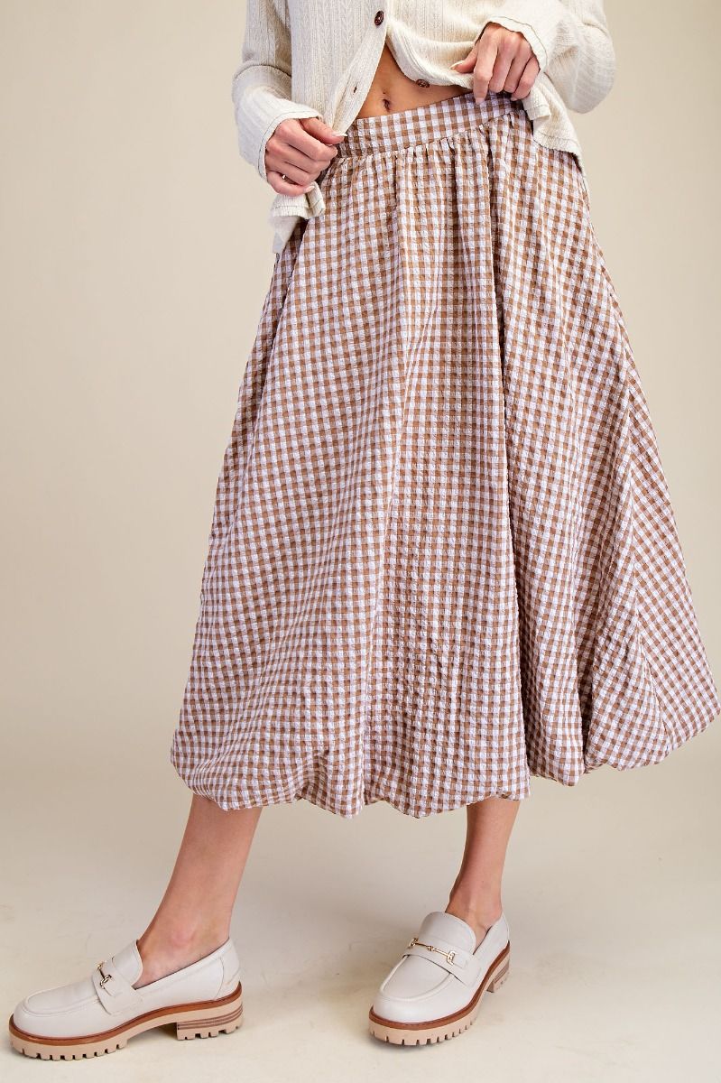 Person wearing a plaid skirt and white shoes on a plain background