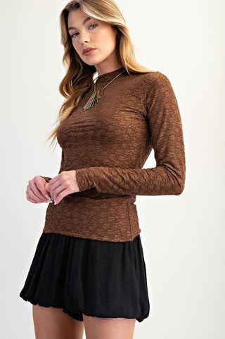 Woman wearing a brown long-sleeve top and black skirt on a white background
