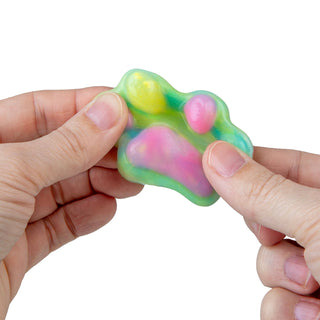 Colorful squishy toy held between fingers on a white background