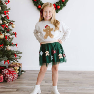 Girl wearing green sequin gingerbread tutu skirt with white holiday sweatshirt