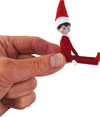 Tiny elf doll in red outfit and hat held between fingers